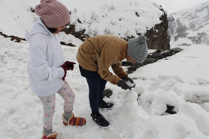 People playing in the snow near a cliff
