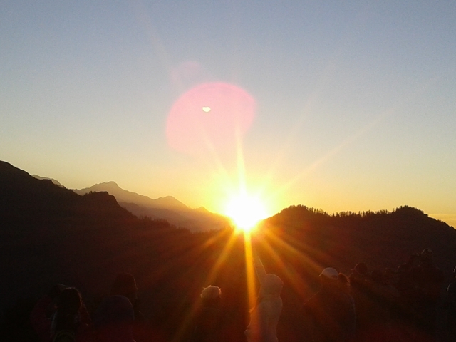       Sunrise over mountains with a pink hue.
  