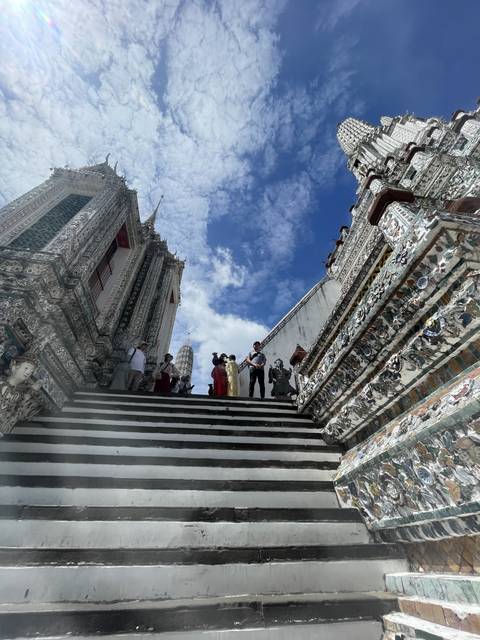       Ornate temple steps with visitors and sky view.
  
