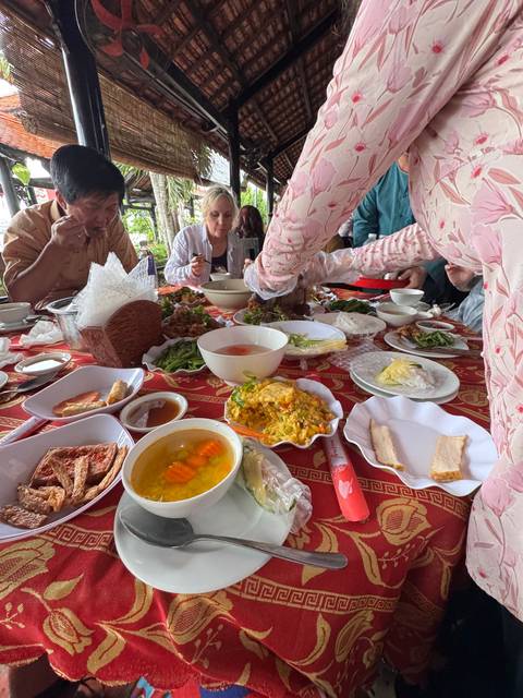       A variety of dishes on a dining table, surrounded by people.
  