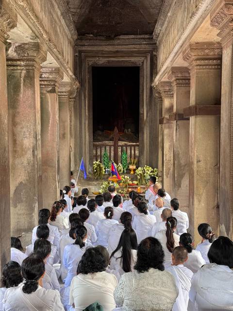 Group of people in white clothing inside a temple-like structure.