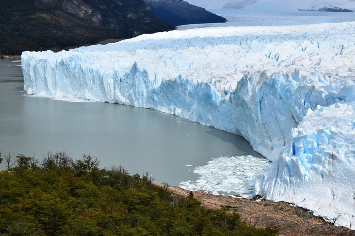       Massive glacier forming a wall along a lake shoreline.
  