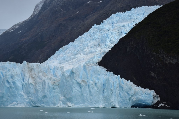       Icy slope meeting a snow-dusted mountain ridge.
  