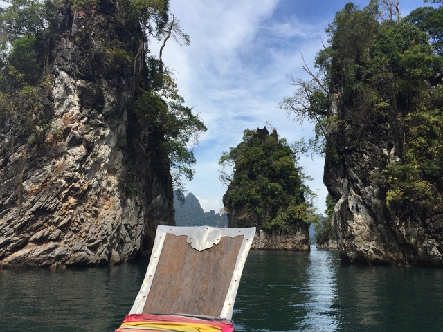 A boat navigating through towering limestone cliffs.