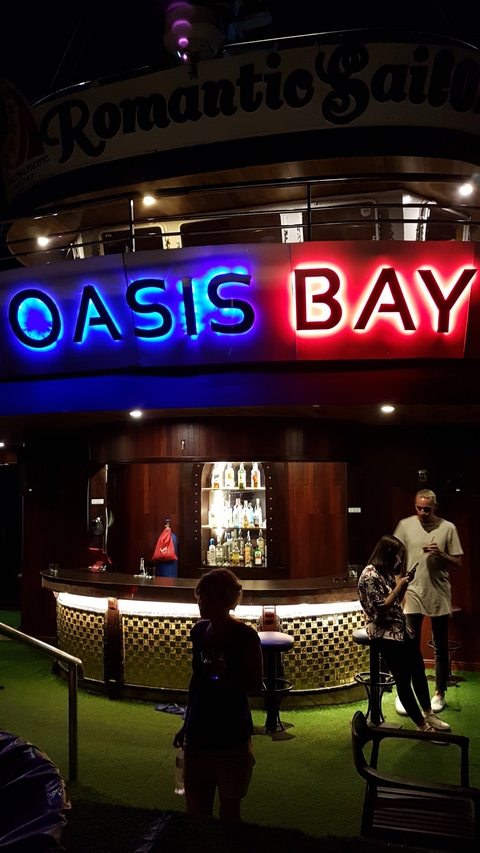 Oasis Bay sign with people at a bar.