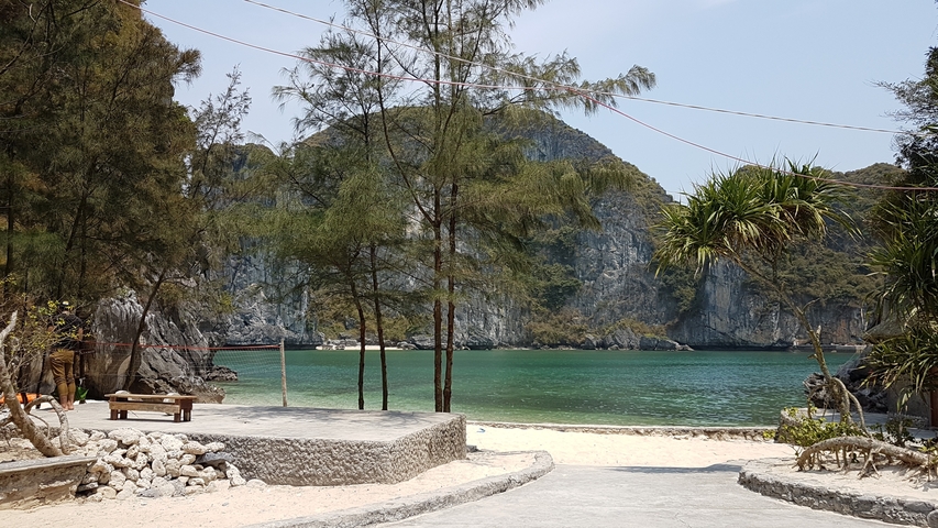Pathway leading to a scenic beach surrounded by cliffs.