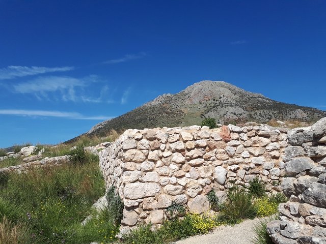 Stone ruins with a mountainous backdrop and clear blue sky.
