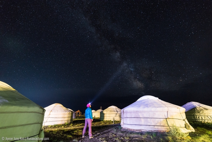       Person stargazing in a yurt camp under a starry sky.
  
