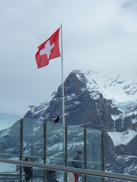 Snowy mountain peak with a Swiss flag.