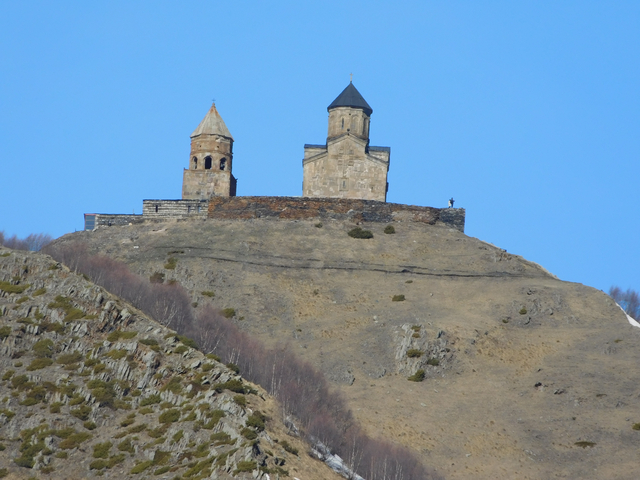 Ancient church complex on hilltop against a clear blue sky.