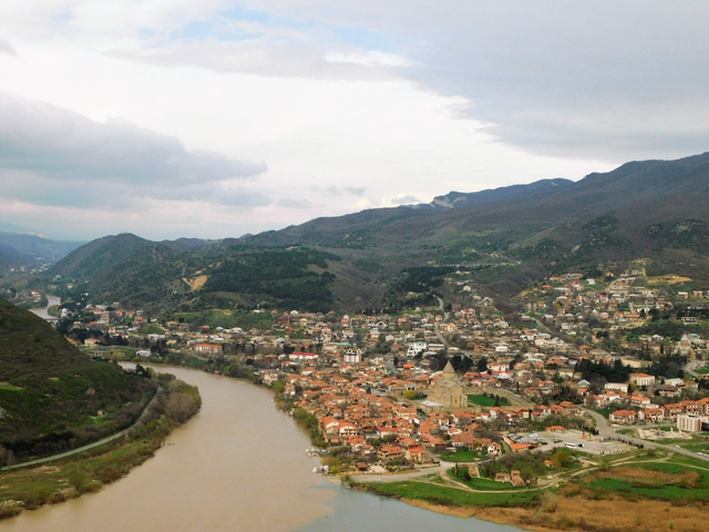 Aerial view of a city with river and surrounding hills.