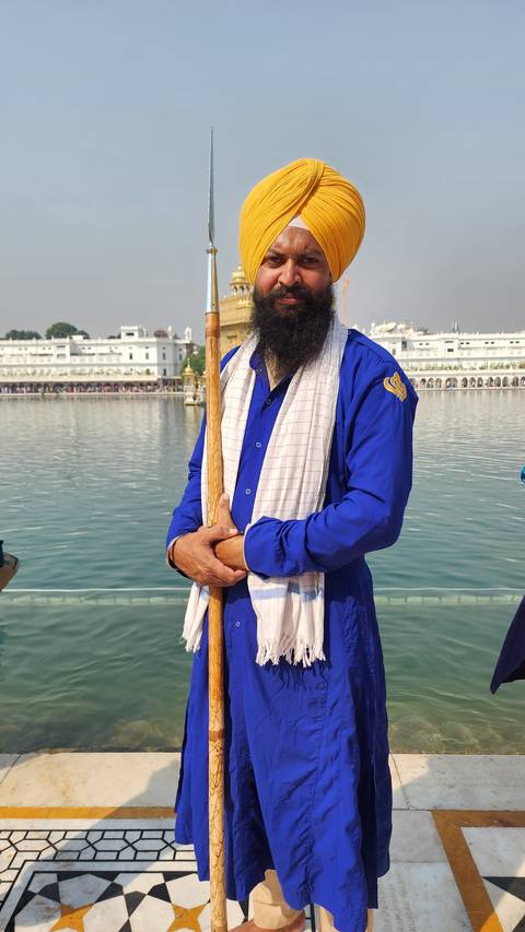       Man in traditional attire standing by water.
  
