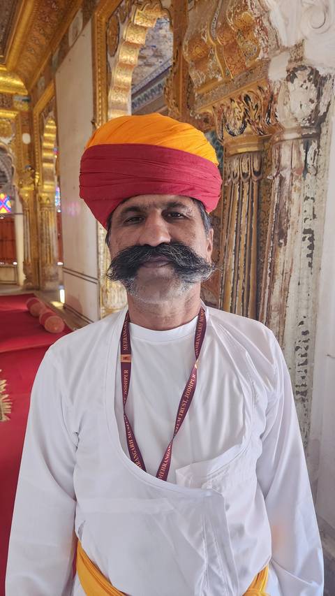       Man in traditional attire posing indoors.
  