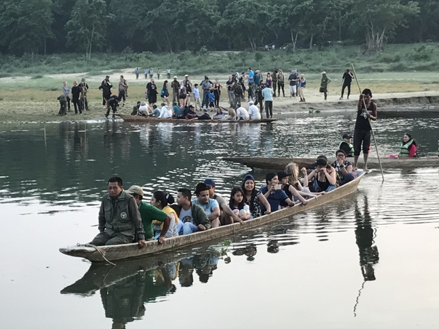 People in wooden boats rowing on a river.