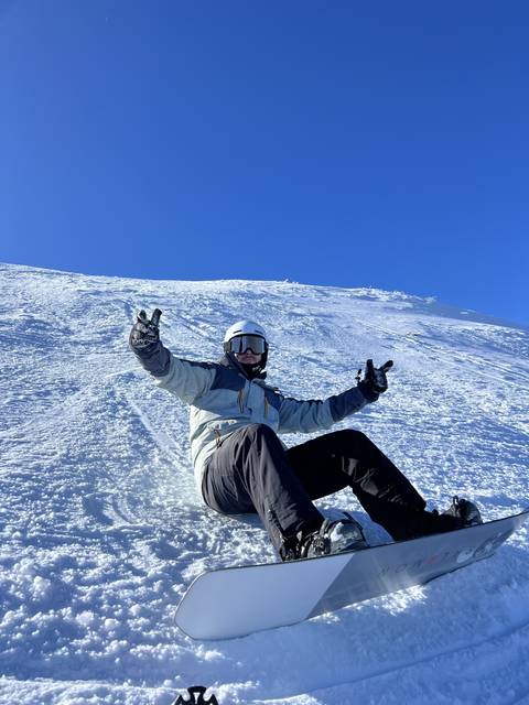 Person snowboarding on a snowy slope with clear sky.