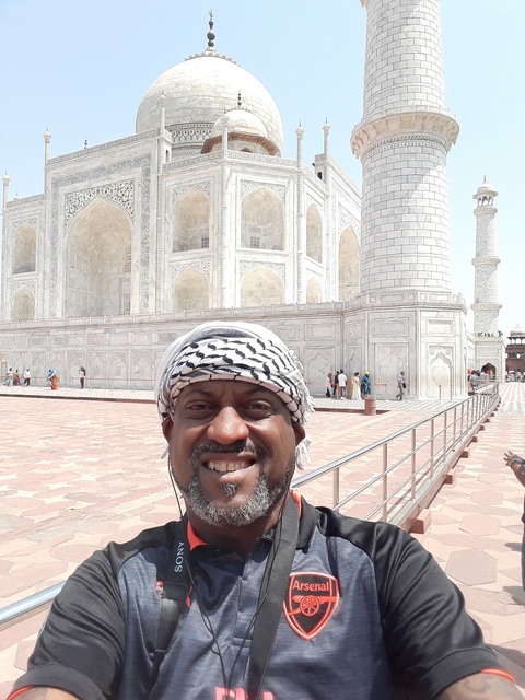       A man smiling with the Taj Mahal in the background.
  