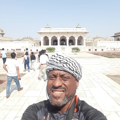      A man standing in front of a historical building with people in the background.
  
