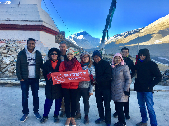       Group holding an Everest banner with mountains in the background.
  