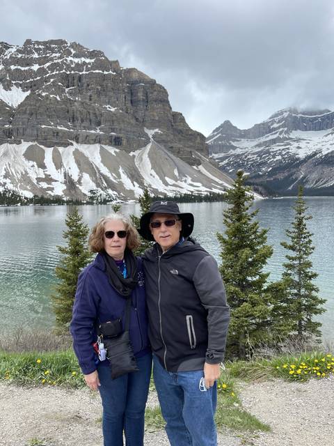 Couple posing by a mountainous lake.