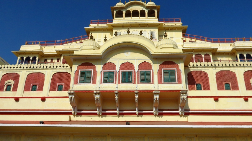       A majestic palace facade with detailed architecture under a clear blue sky.
  