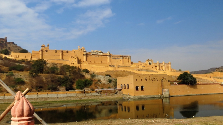 A large fort reflected in a water body with clear skies.