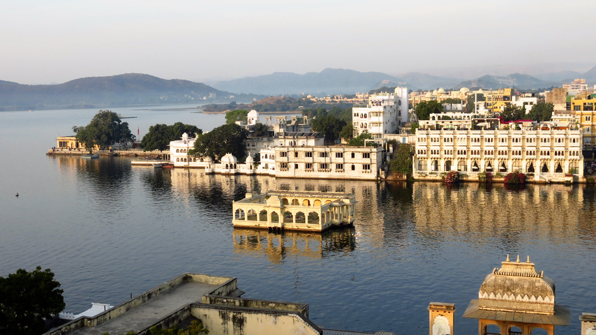       A panoramic view of buildings by a lake reflecting on the water.
  