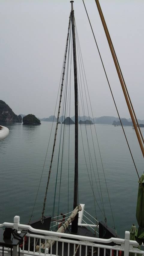       View of a ship's mast and sails against the sea.
  