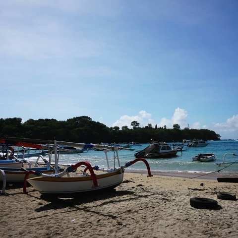 Sandy beach with boats anchored in shallow waters.