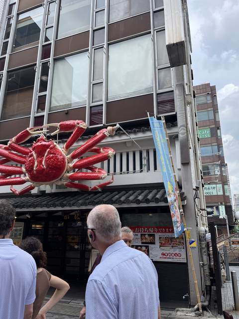       People walking by a large crab sign on a building.
  