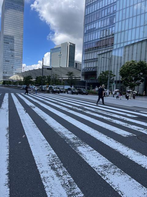       People crossing a large street with skyscrapers in the background.
  