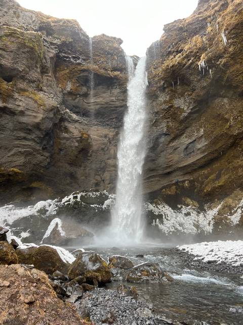       View of a waterfall from behind, surrounded by rocks.
  