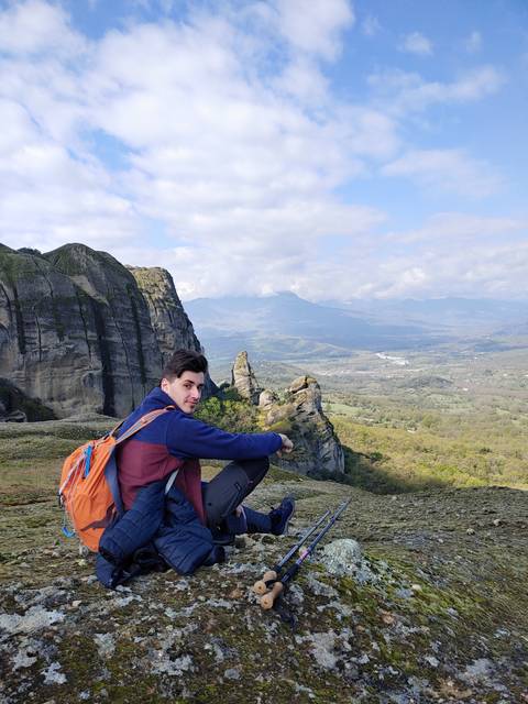 Person sitting on a rock ledge with hiking gear.