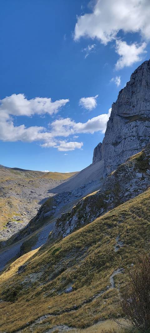       Rocky hill with grass and a clear sky.
  