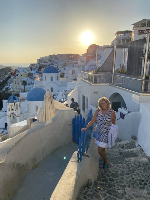       Woman posing on a terrace with traditional white buildings.
  