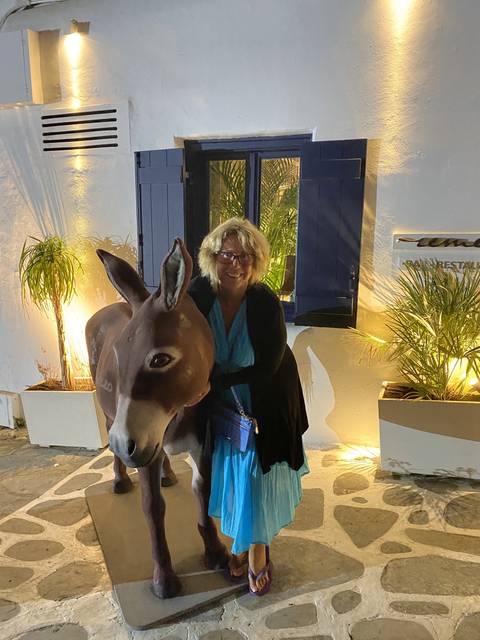       Woman posing with a statue of a donkey at night.
  