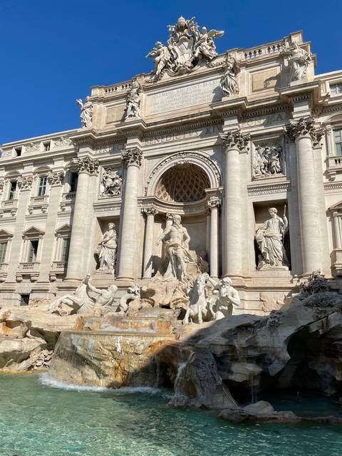 Trevi Fountain in Rome under a clear blue sky.