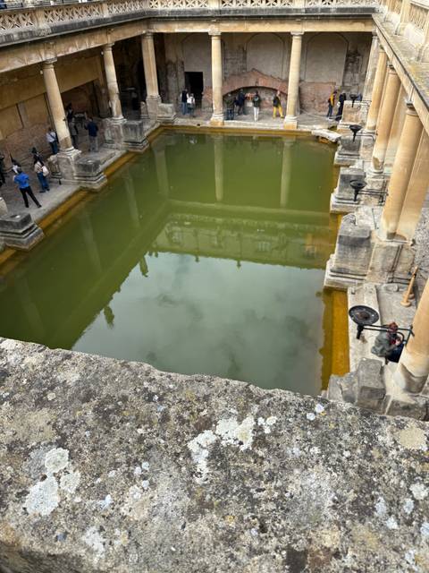 A historic Roman bath with green water.