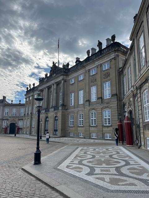       Large historic building with flags and sculptures.
  