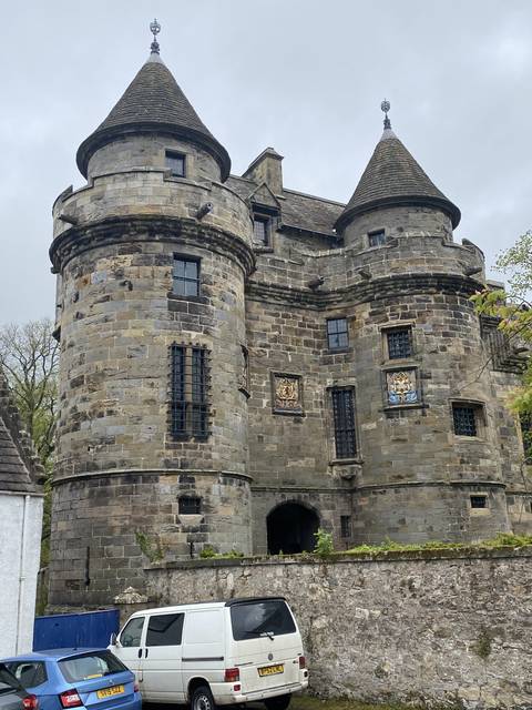       Stone castle with conical towers against a cloudy sky.
  