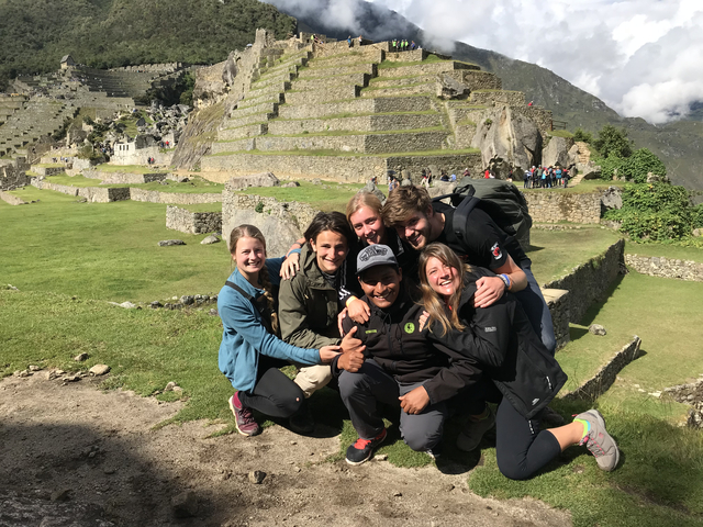 Group of people posing in front of historic stone terraces.