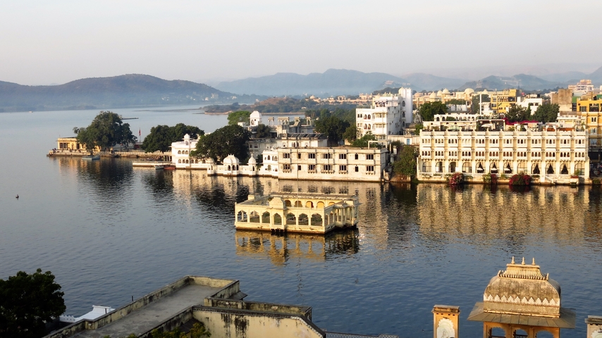 Lake view with historic buildings and mountains in the background.