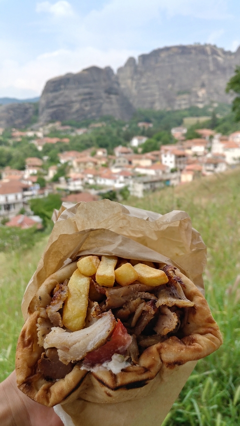 Takeaway wrapped sandwich with town in the background.