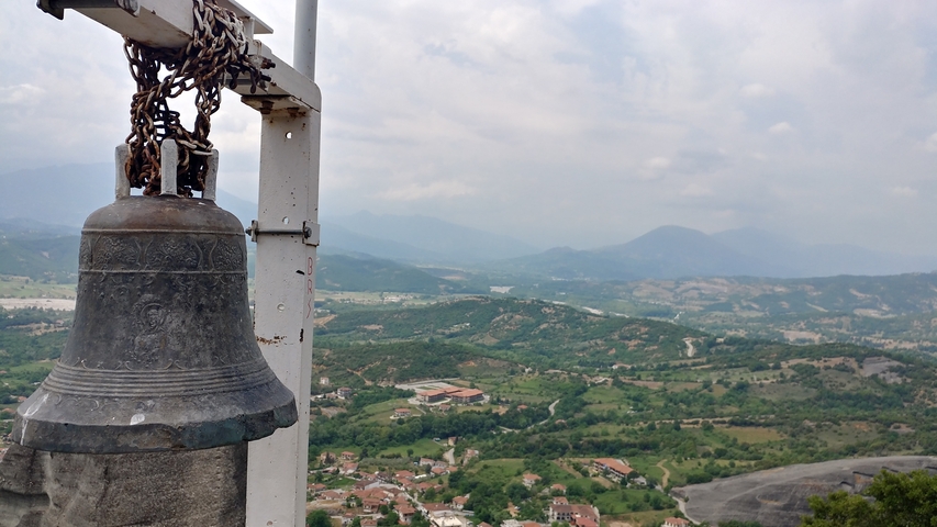 View from a hill with a bell, overlooking a green landscape.