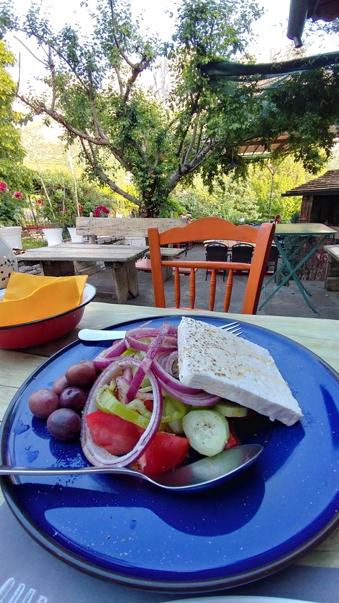Plate of Greek salad with cheese, on an outdoor table.