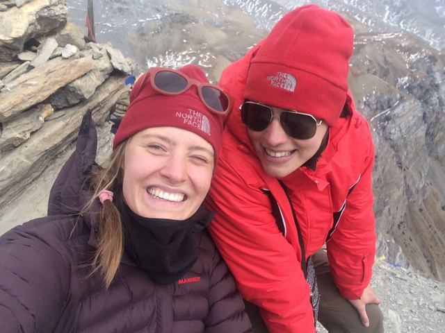       Two people posing with mountains in the background.
  
