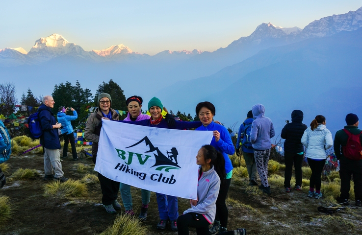       A group holding a banner with mountain scenery.
  