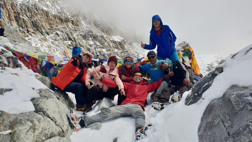 Group of people posing on a snowy mountain path.