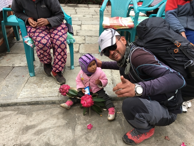 Man with a child and pink flowers in a vibrant street setting.