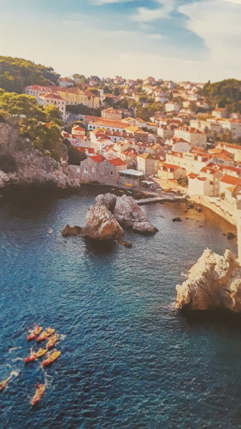       An aerial view of a coastal city with rocky outcrops.
  