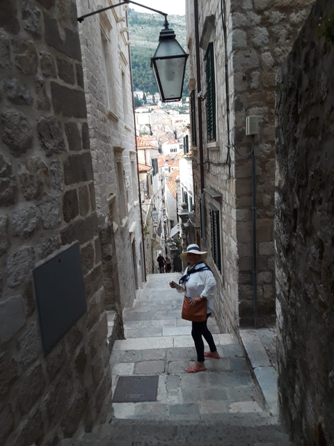       A person standing in a narrow stone alleyway.
  